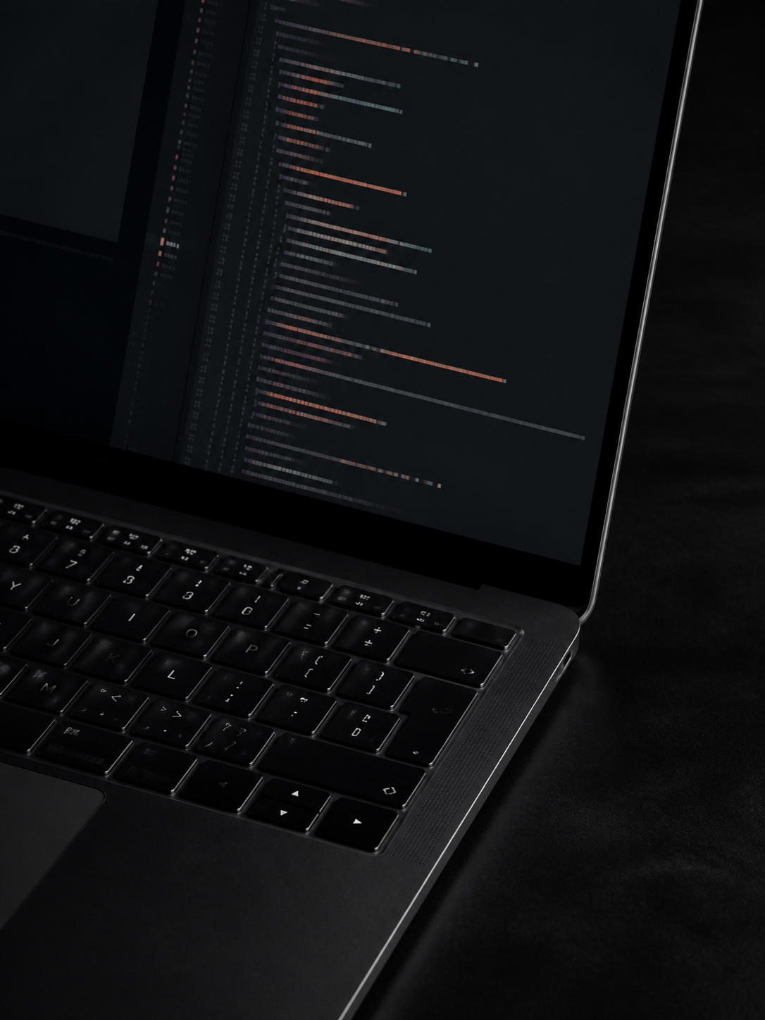 Dark laptop and abstract code editor photographed at an oblique angle